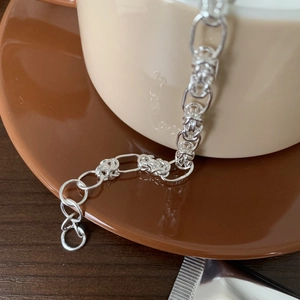Macro shot of S925 sterling silver woven chain bracelet draped over a beige mug