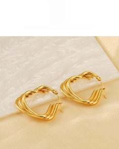Detail of 18K gold plated earrings with multilayered curved lines on marble background