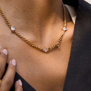 Gros plan d'un collier en titane doré avec cinq zircons carrés porté par un modèle