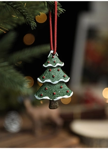 Detailed view of a green resin Christmas tree ornament with white snow and red dot accents
