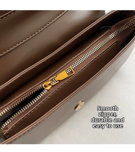 Detail view of smooth golden metal zipper and internal compartment on dark brown leather bag