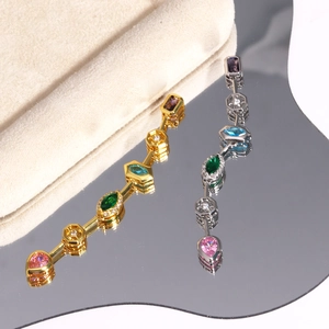 Close-up of gold and silver tassel pendants with colorful zircon stones on a mirror