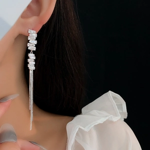 Detail of silver long tassel earrings with sparkling rhinestones worn on ear