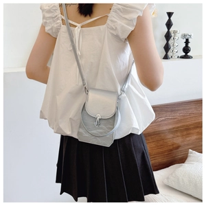 Sac à bandoulière argenté à texture froissée et boucle en métal sur un modèle