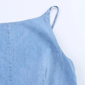 Gros plan détaillé sur la texture du denim bleu clair et les coutures des bretelles