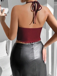 Detail view of burgundy knitted halter top and black leather skirt from back angle