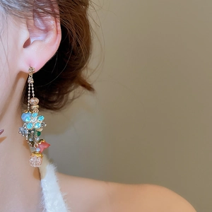 Close-up of dangling drop earrings with blue flower pendant and colorful beads on model