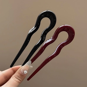 Detail of wavy U-shaped hair pins in black and burgundy resin for elegant hair styling