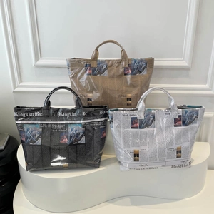 Three retro newspaper print tote bags in brown black and white on a display stand