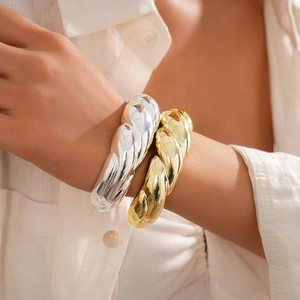 Close-up of twisted rope texture on a chunky gold and silver open cuff bracelet