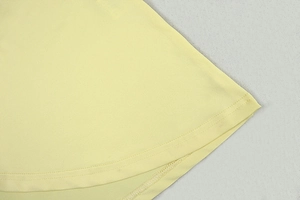 Detailed close-up of double-needle hem stitching on a pale yellow A-line dress