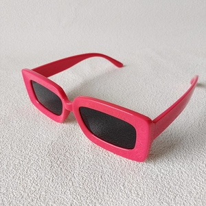 Macro shot of stylish square hot pink sunglasses with thick glossy frames and dark lenses