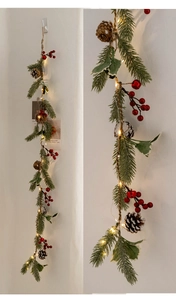 Close-up detail of Christmas garland with pine cones, red berries and warm LED lights