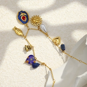 Detail of 18K gold-plated necklace with sun, heart, pearl, and blue stone pendants