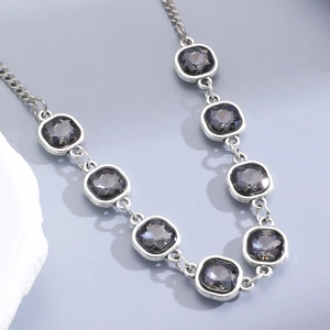 Detail of square dark grey crystals set in silver metal frames on a sleek necklace