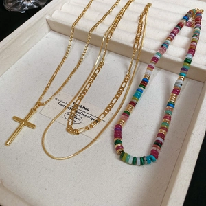 Detailed view of layered 18k gold plated cross necklaces with bohemian colorful bead chain