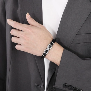 Close-up of black braided leather bracelet with silver infinity symbol on male wrist
