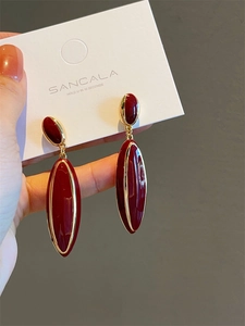 Macro shot of vintage style burgundy enamel teardrop earrings with gold plating