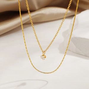 Elegant double-layered gold necklace with sparkling zircon pendant on satin background