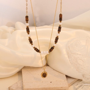 Double-layered gold necklace with brown beads and tiger eye pendant on white silk