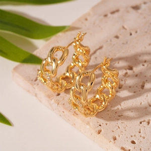 Macro view of gold chain link hoop earrings with zircon pavé setting on stone