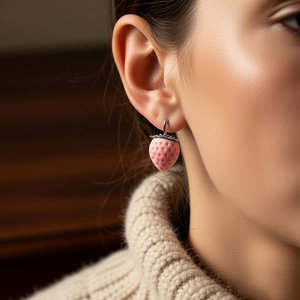 Sweet pink flocked strawberry pendant earring worn by model with cozy knit sweater