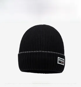 Detail view of black ribbed knit beanie with stylish rectangular cloth patch and folded brim