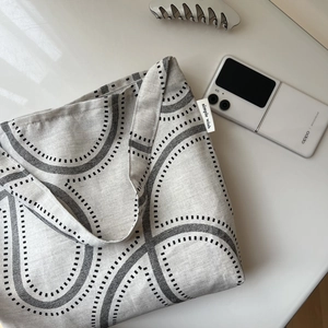Detail of linen tote bag featuring geometric black patterns and simple wish woven label
