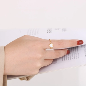 Close-up of a minimalist gold heart ring worn by a model holding a magazine