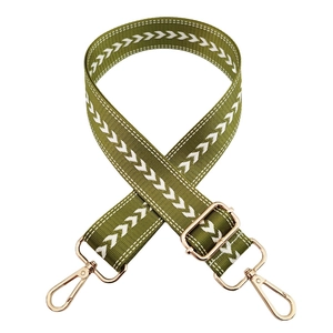 Detail of adjustable green nylon strap with white arrow pattern and gold metal buckles