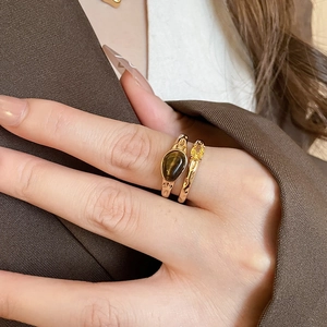 Detail of tiger eye stone ring and hammered metal band worn on model fingers