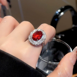 Macro view of luxury oval red ruby ring with sparkling baguette diamonds on model's hand