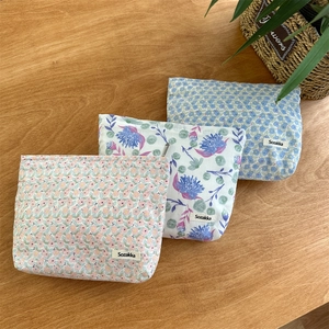 Flat lay of floral cotton makeup bags with top zippers on a wooden table setup