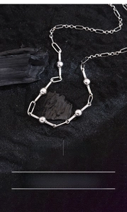 Macro detail of minimalist silver-plated ball chain necklace with lobster clasp closure