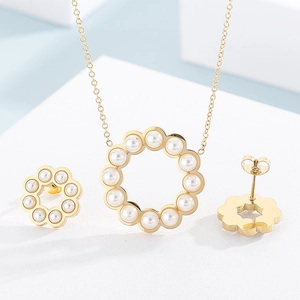 Dettaglio di un set di collana e orecchini dorati con perle su supporto bianco
