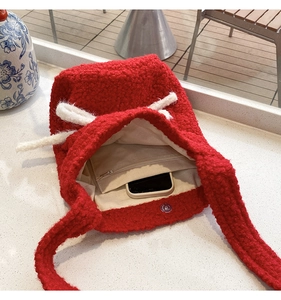 Detail view of red plush tote bag interior with beige lining and zip pocket