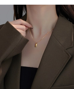 Detail of minimalist gold necklace with rectangular V-letter pendant on model