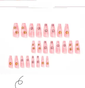 Detailed view of 24 pieces of long ballet pink press-on nails with yellow smiley faces