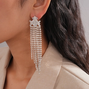 Close-up of geometric diamond tassel earrings with sparkling rhinestones on model