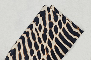 Close-up detail of smooth leopard print fabric with black and tan animal pattern