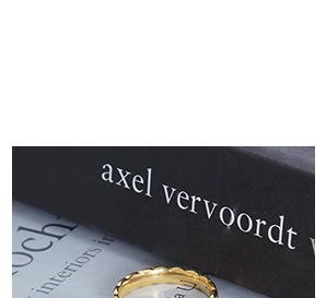 Macro shot of gold stainless steel ring with wavy texture resting on a black book