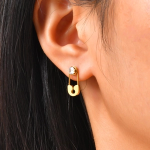 Macro shot of gold paperclip earring with round zircon stud on a model's ear