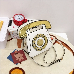 Detailed close-up of retro telephone shoulder bag in white and gold mirror finish