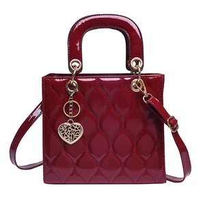 Detail of red patent leather handbag with quilted stitching and heart metal charm