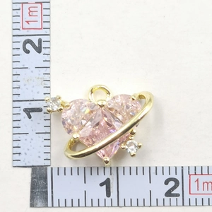 Macro detail of a pink heart-shaped crystal pendant with gold trim and side stones