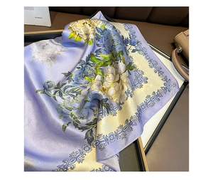 Detail of a purple silk scarf featuring elegant floral patterns next to a leather bag