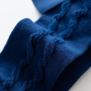 Close-up of navy blue knit princess socks with classic cable pattern and bow detail