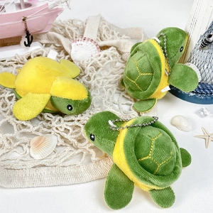 Close-up of three cute plush turtle keychains on a sea-themed background with shells