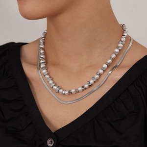Layered necklace set with white pearls and silver snake chain worn on female neck
