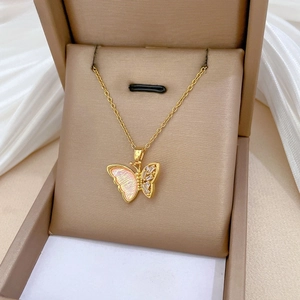 Detailed macro view of a gold-tone butterfly pendant with pink shell wings and zircons